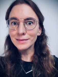 A woman with glasses and long hair wearing gold frames.