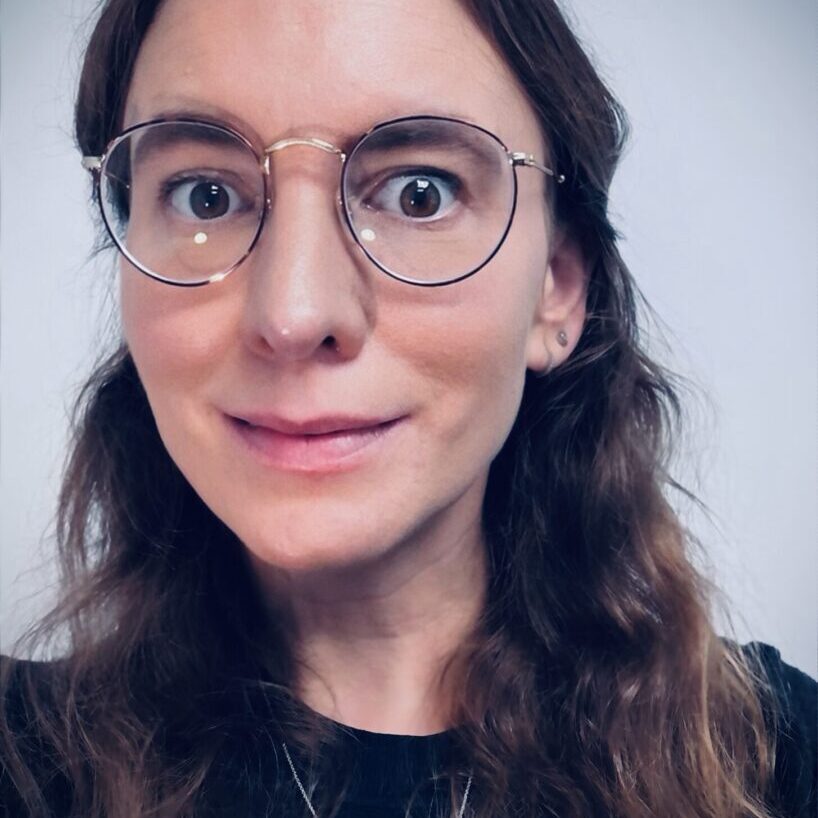 A woman with glasses and long hair wearing gold frames.